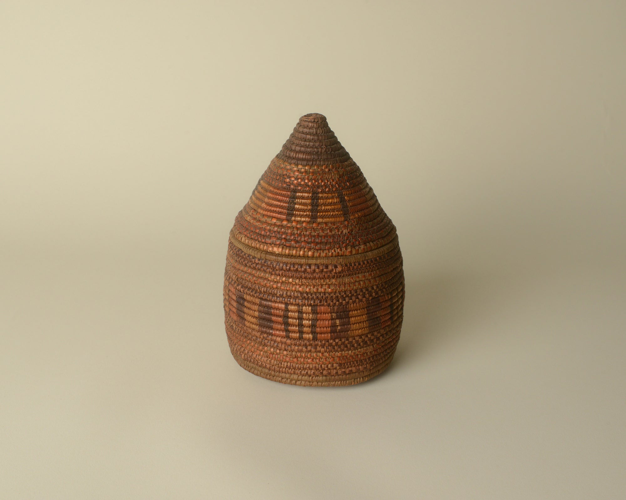 Small West African woven basket with pointy lid.